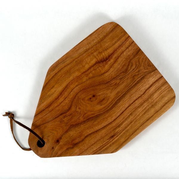 Handmade reclaimed wood cutting board with leather hanging strap. Angled house shape. White background.