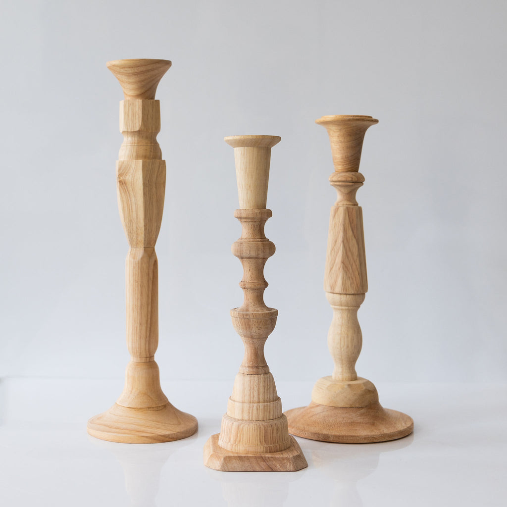 Natural hardwood hand-turned taper candlesticks in a group of three different heights.