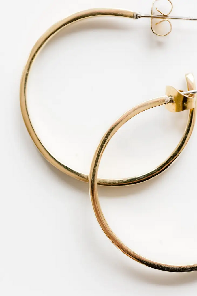 Detail shot of gold hoop earrings on a white background.