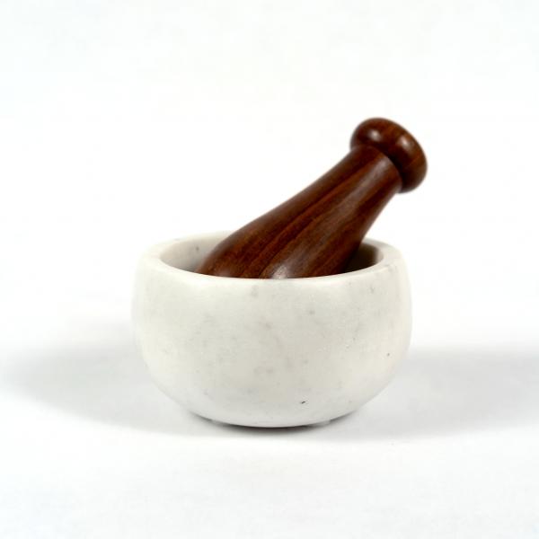 White marble mortar bowl with wood pestle on a white background.
