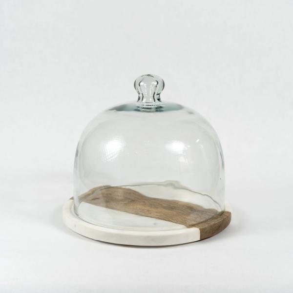 Glass cloche sits atop a white marble and wood tray. White background.