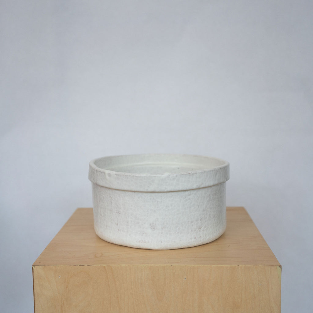 Large white ceramic bowls on a wood platform in front of a white background.