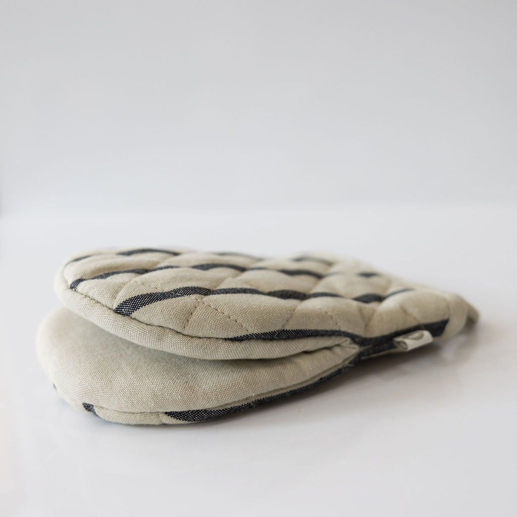 Cream oven glove with black stripes on a white background.