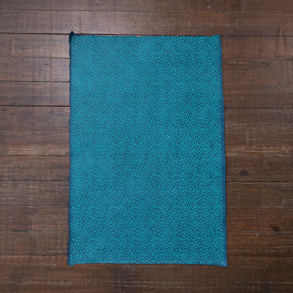 Handmade and printed paper gift wrap. Pattern is repeat turquoise rain drops on blue background.