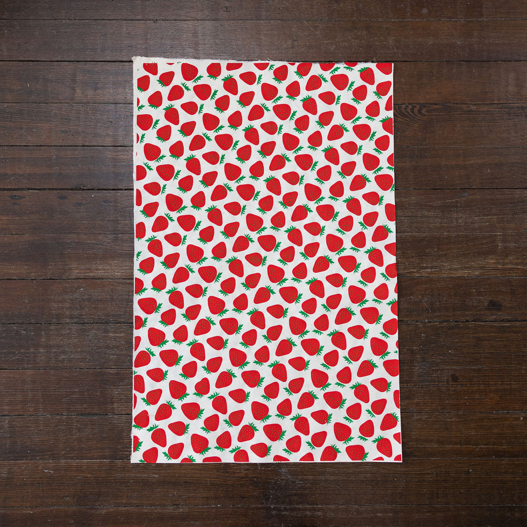 Handmade and printed paper gift wrap. Pattern is repeat strawberries on white background.