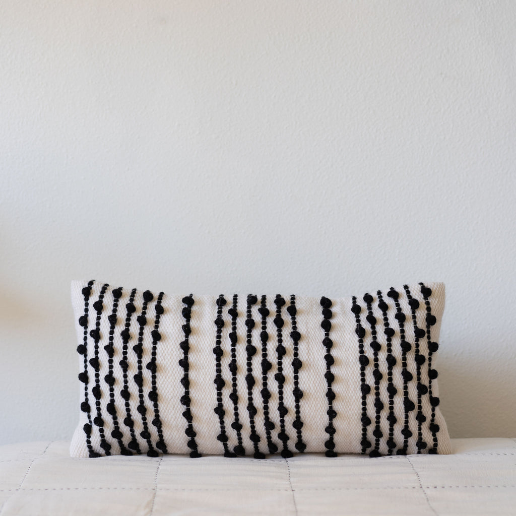 Rectangle wool woven pillow featuring a black striped pom tufted design.