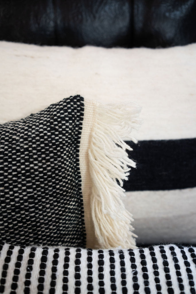 Detail shot of many textured black and cream wool pillows.