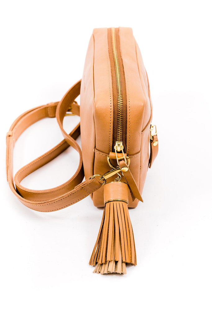 Tan leather rectangular purse with interchangeable chain and  leather straps. Leather strap includes a big tan leather tassel. Side view.