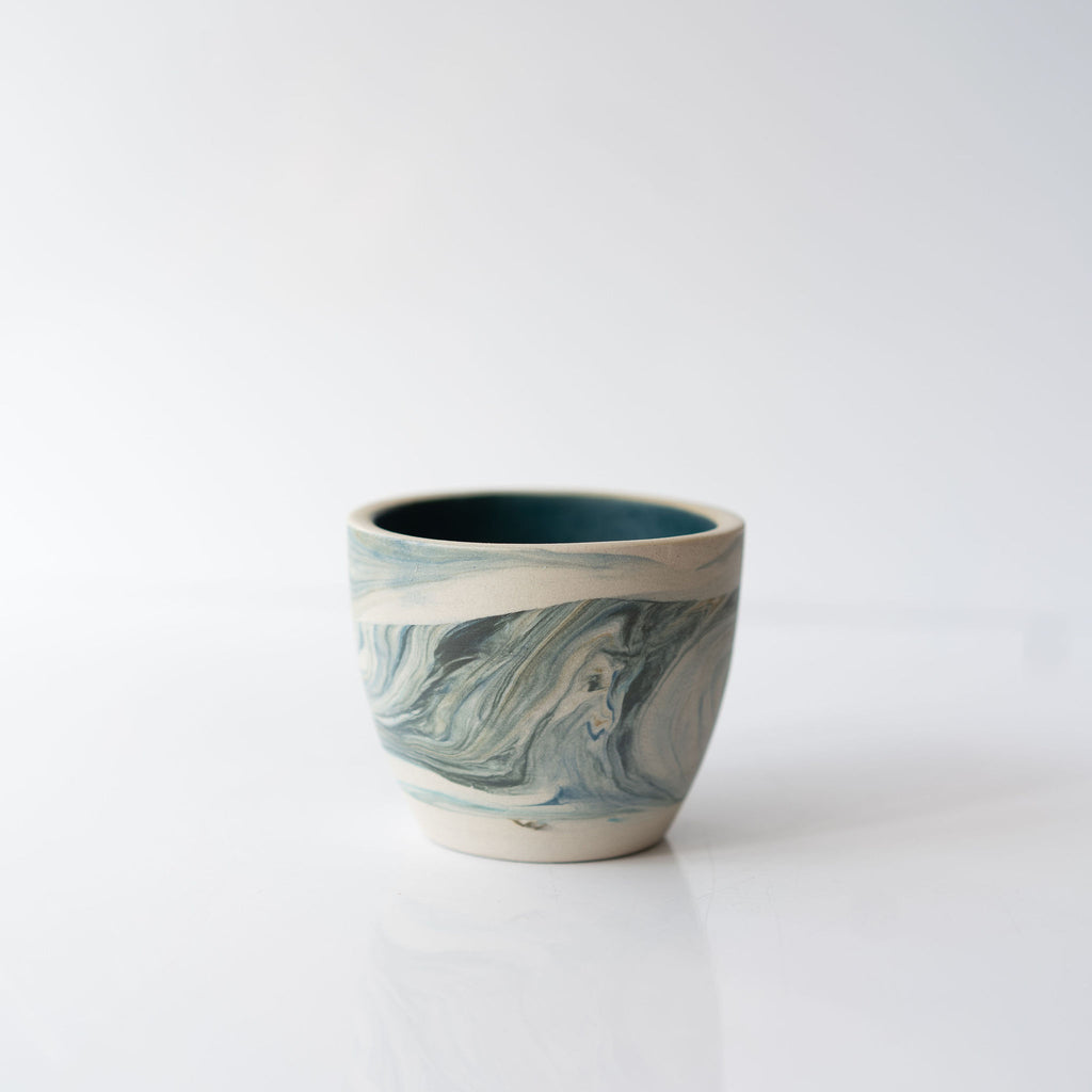 One blue marbled ceramic cup with a solid blue interior.
