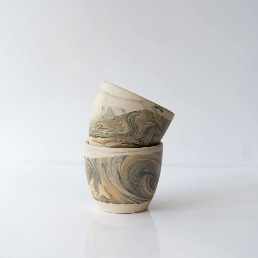 Stack of two black and tan marbled ceramic cups.