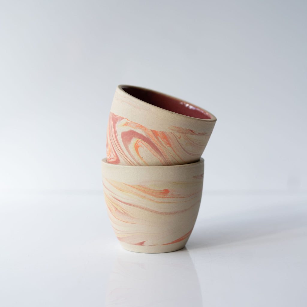 Stack of two pink and orange marbled ceramic cups.