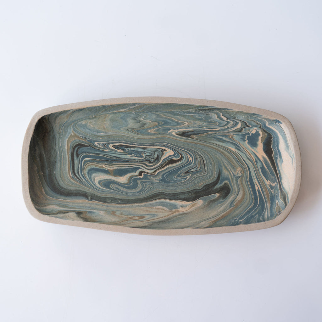 One marbled rectangular plate in shades of blue with pops of tan. Plate has a slightly raised edge.