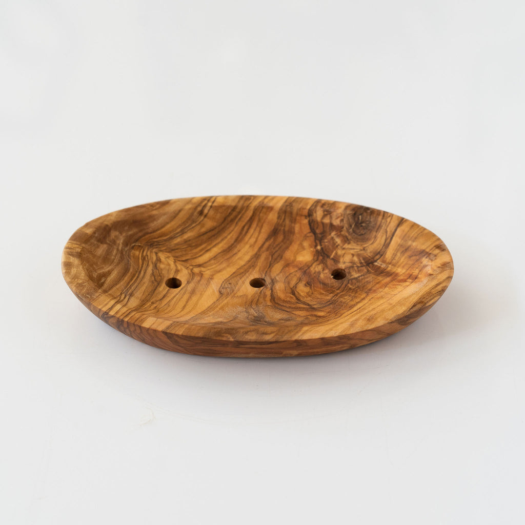 Oval olive wood soap dish with drainage holes. Light gray background.