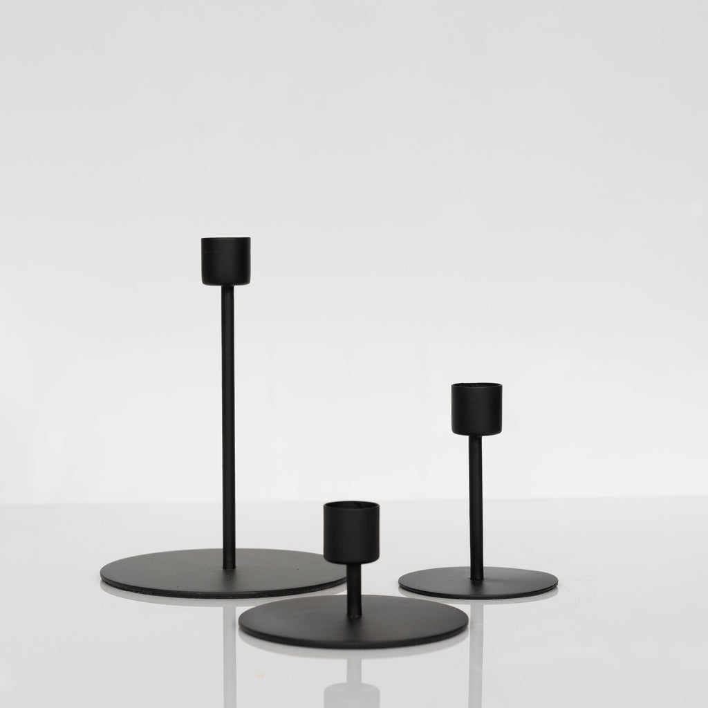 Trio of modern matte black taper candle holders sitting together.
