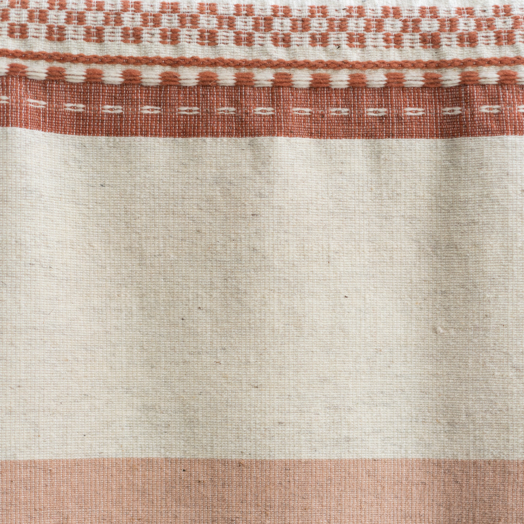 Naturally dyed wool blanket in tones of terra cotta and cream with varying widths of color blocking, stripes, and traditional Oaxacan weaving techniques. Detail shot.