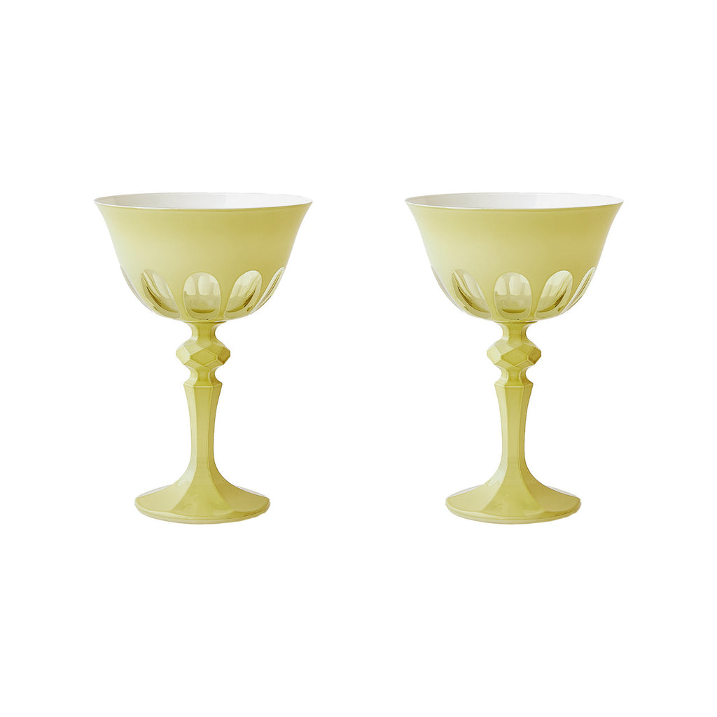 Pair of creamy yellow toned tall handblown curvy glasses. Skinny stem with a round base topped with a curved bowl with a mix of opaque and transparent arches. White background.