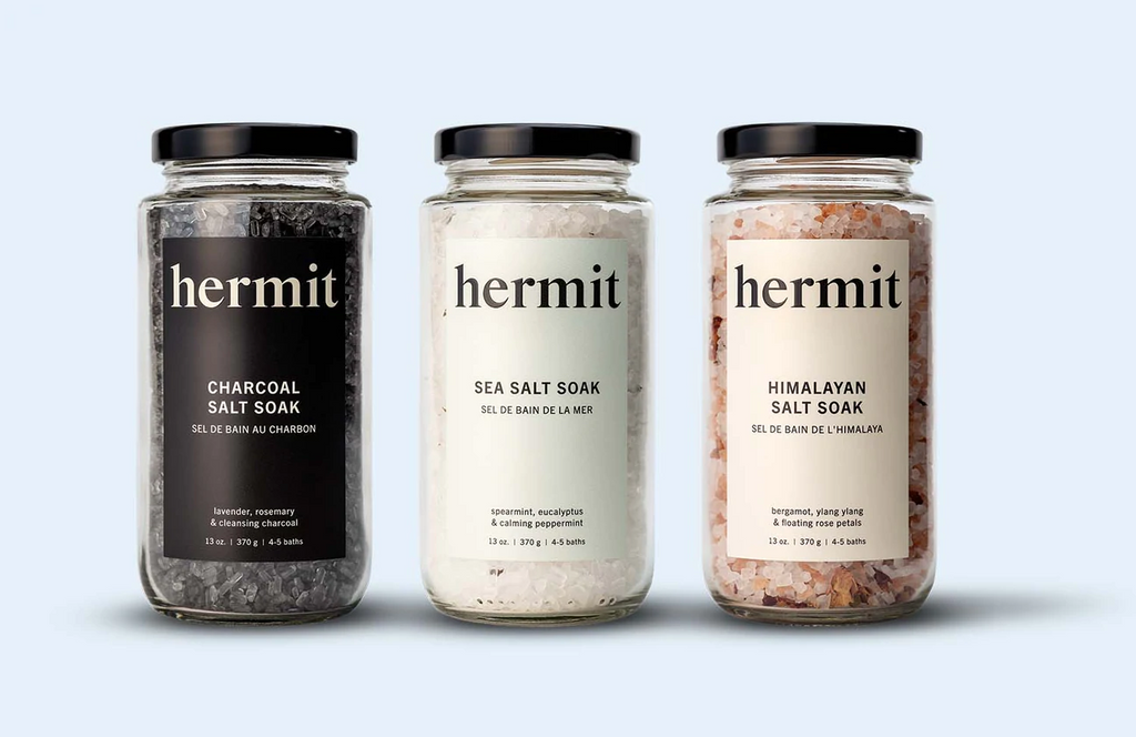 Three Salt Soaks sit in a row on a light gray background. Charcoal, sea salt, and himalayan salt.