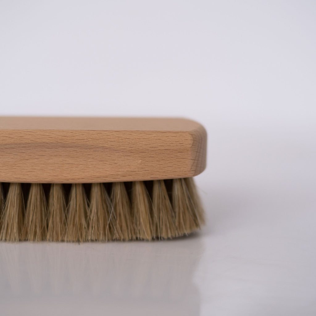 Detail view of a beechwood and horse hair shoeshine brush on white background.