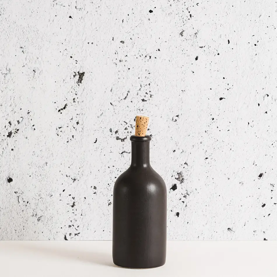 Matte Black stoneware olive oil bottle with cork sits against a marbled background.