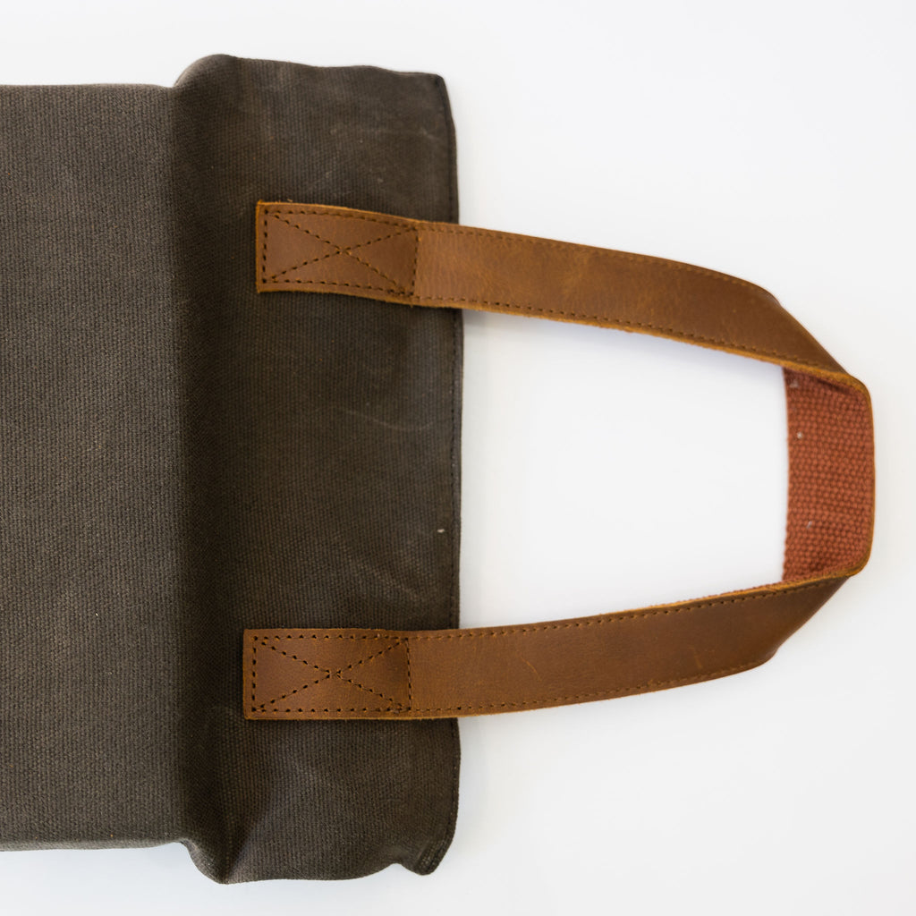 Brown waxed canvas foam kneeler with tan leather handles. Close view of leather handle.