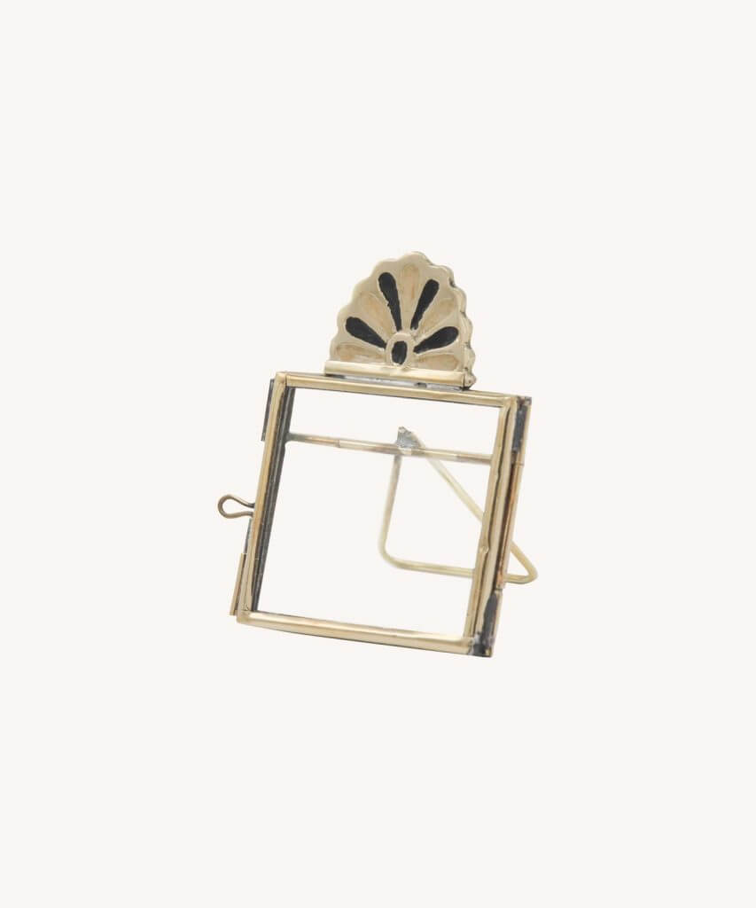 Small brass frame with simple border and a black and brass art deco petal fan on top. White background.