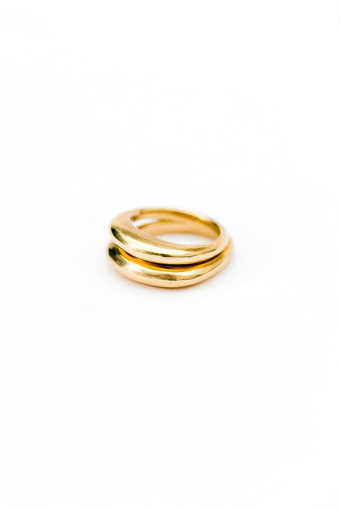 Two brass rings that are wider on the top are stacked together on a white background.